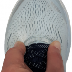 Pinching the top of the shoe at the end of the laces indicating how to test shoe depth