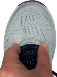 Pinching the top of the shoe at the end of the laces indicating how to test shoe depth