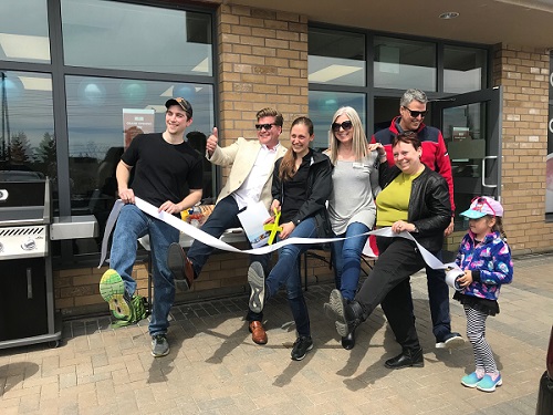 Owners of On the Ball Orthotics, City Councillor, Rainbows Representative, and two members from the chamber of commerce cutting the ribbon for the grand opening. All have one foot in the air