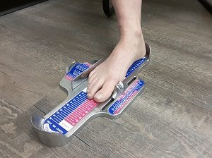 Right foot getting measured on a brannock device to determine the proper shoe size.