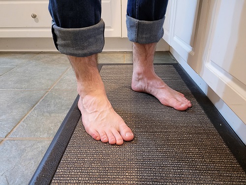 Standing on a mat to reduce pressure on the outside of the feet