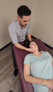 Massage therapy fully clothed. Male therapist moving the neck.