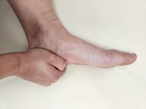 Hand holding the heel of the foot